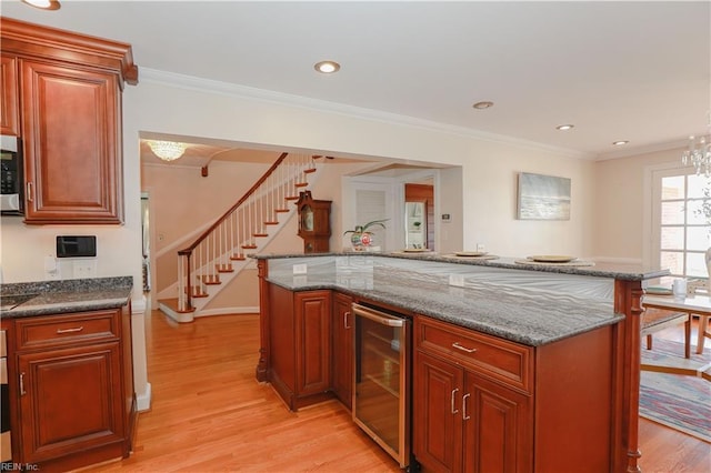 kitchen with light hardwood / wood-style floors, crown molding, a kitchen island, and wine cooler