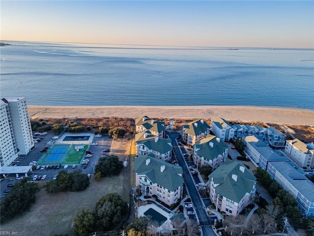 aerial view at dusk featuring a beach view and a water view