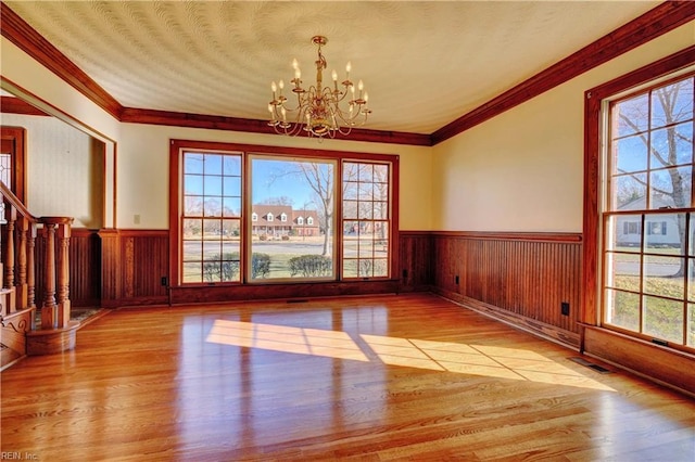 unfurnished dining area featuring a notable chandelier, light wood-type flooring, and a wealth of natural light