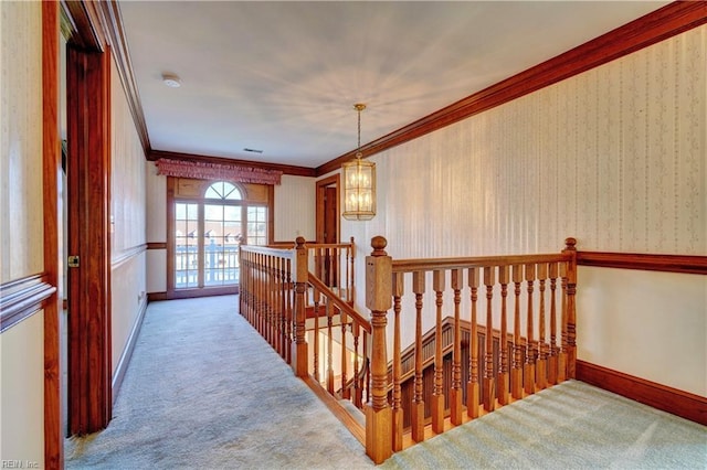 hall with ornamental molding, an inviting chandelier, and carpet floors