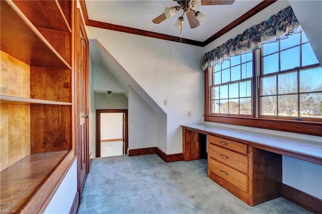 unfurnished office with built in desk, ceiling fan, crown molding, and light colored carpet