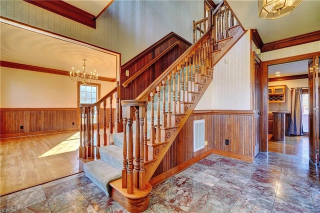 stairway featuring an inviting chandelier, ornamental molding, and a wealth of natural light