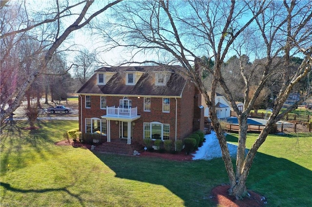 view of front of house featuring a balcony and a front yard