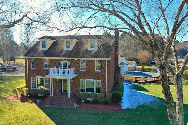 view of front of property featuring a balcony and a front yard