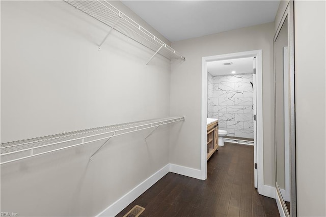 walk in closet with dark hardwood / wood-style floors