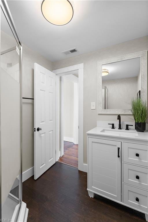 bathroom with walk in shower, vanity, and hardwood / wood-style flooring