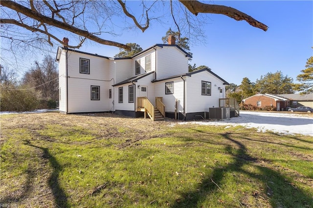 back of house with central air condition unit and a lawn