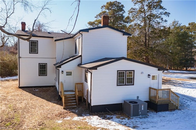 snow covered house featuring central AC unit