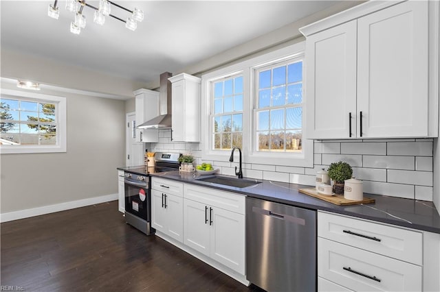 kitchen with stainless steel appliances, wall chimney range hood, decorative backsplash, white cabinets, and sink