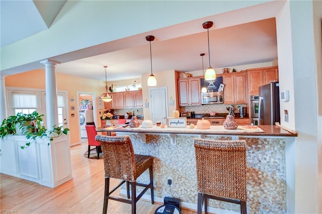 kitchen featuring fridge, backsplash, decorative columns, and kitchen peninsula