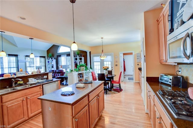 kitchen featuring sink, a center island, appliances with stainless steel finishes, and decorative light fixtures