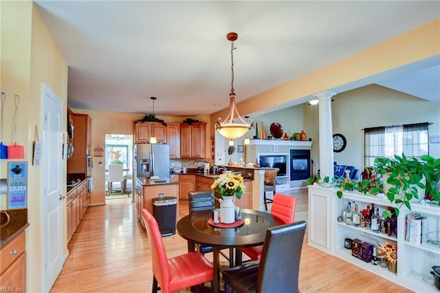 dining space featuring decorative columns and light hardwood / wood-style flooring