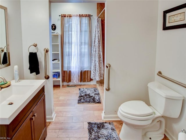 bathroom featuring a shower with shower curtain, hardwood / wood-style floors, vanity, and toilet