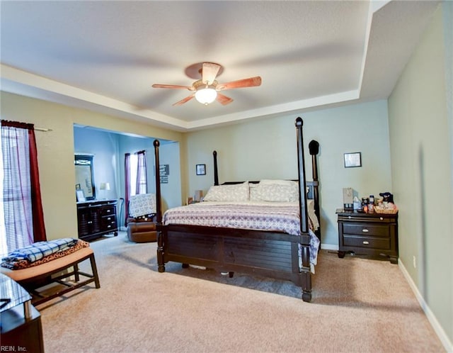 carpeted bedroom with ceiling fan and a tray ceiling