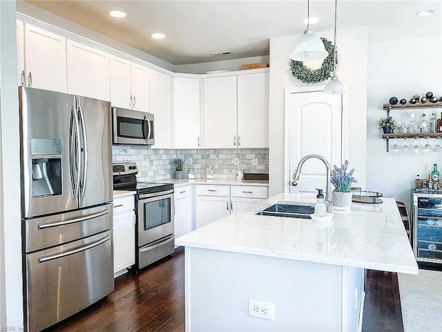 kitchen with sink, stainless steel appliances, an island with sink, and white cabinetry