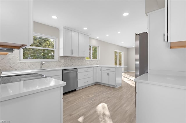 kitchen featuring plenty of natural light, kitchen peninsula, stainless steel appliances, and white cabinets