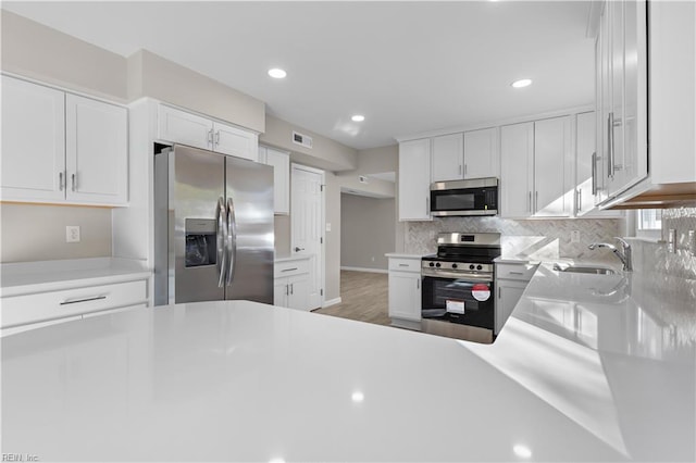 kitchen featuring white cabinets, backsplash, sink, and stainless steel appliances