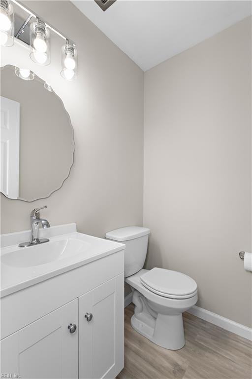 bathroom with toilet, vanity, and hardwood / wood-style floors