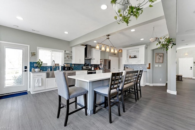 kitchen featuring wall chimney range hood, white cabinets, and stainless steel appliances