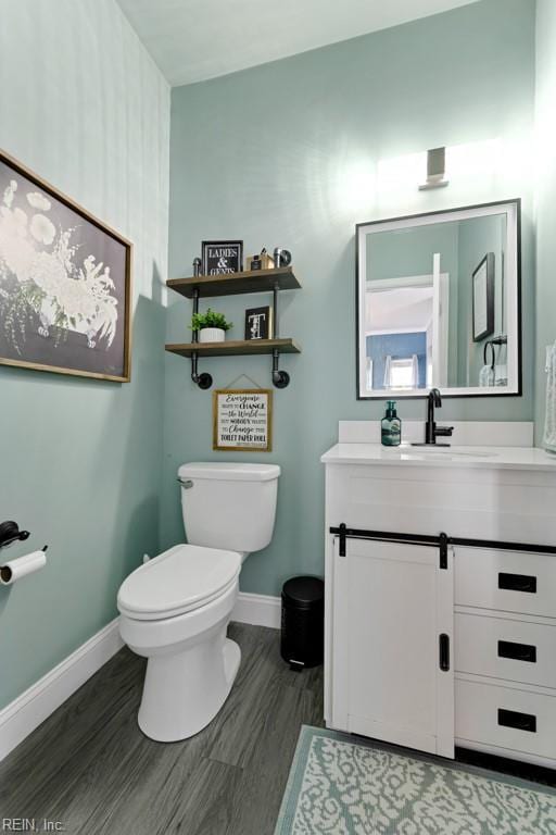 bathroom with toilet, vanity, and wood-type flooring