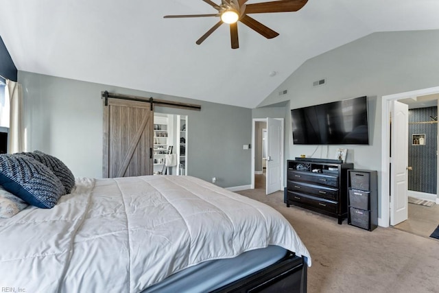 carpeted bedroom with ceiling fan, a barn door, vaulted ceiling, and connected bathroom