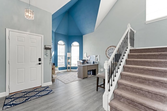 foyer with high vaulted ceiling, wood-type flooring, and a notable chandelier