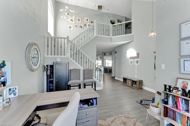 office space featuring a chandelier, wood-type flooring, and a towering ceiling