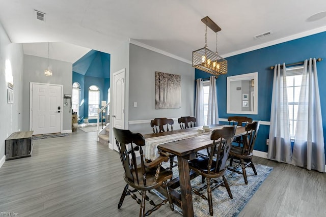 dining area with hardwood / wood-style flooring, vaulted ceiling, a notable chandelier, and a healthy amount of sunlight