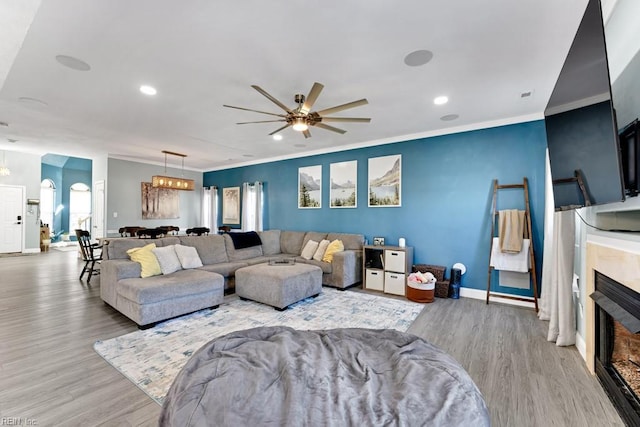 living room with light hardwood / wood-style floors, crown molding, and ceiling fan