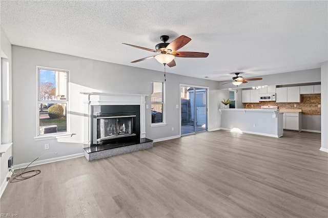 unfurnished living room with a textured ceiling, ceiling fan, and hardwood / wood-style flooring