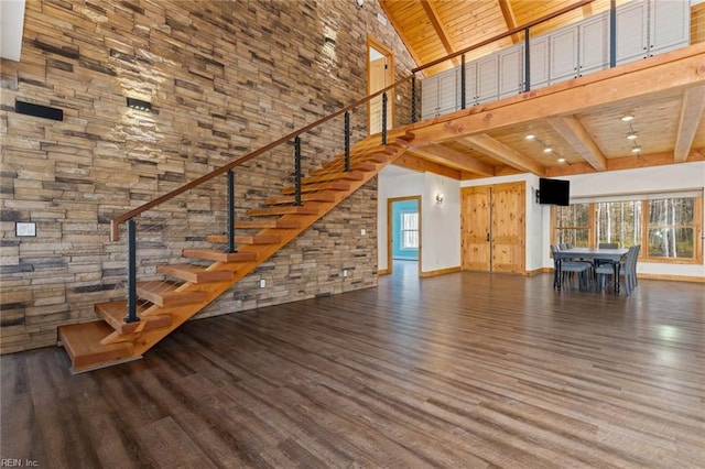 unfurnished living room with wooden ceiling, dark hardwood / wood-style flooring, a towering ceiling, and beamed ceiling