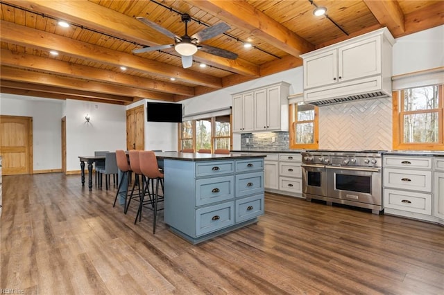 kitchen with decorative backsplash, range with two ovens, white cabinetry, and a center island