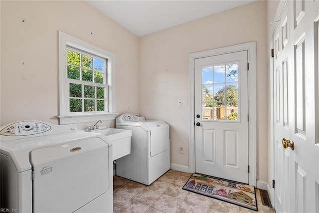 clothes washing area featuring separate washer and dryer, light tile patterned floors, and sink