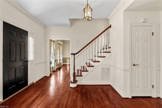 foyer entrance with dark hardwood / wood-style flooring, an inviting chandelier, and ornamental molding