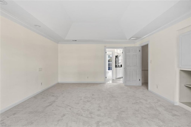 spare room featuring a raised ceiling, crown molding, and light carpet