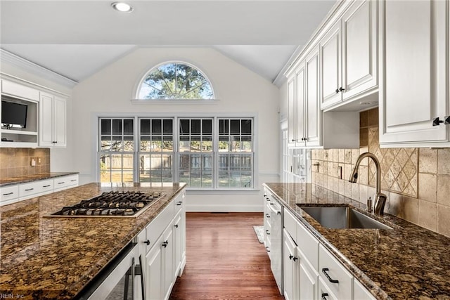 kitchen featuring lofted ceiling, white cabinetry, appliances with stainless steel finishes, dark stone countertops, and sink