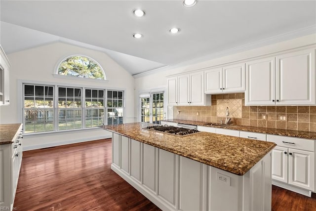 kitchen featuring white cabinets, stainless steel gas cooktop, a kitchen island, sink, and lofted ceiling