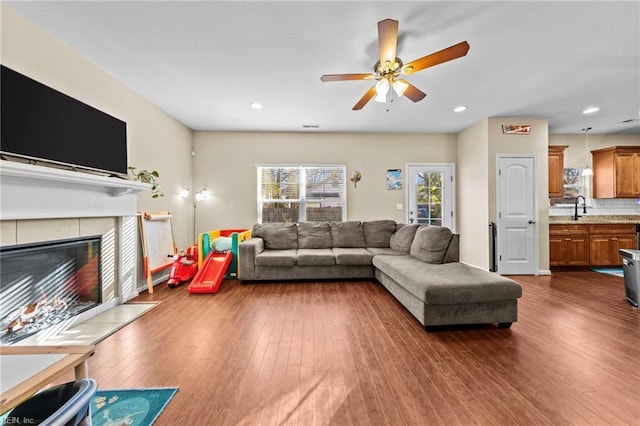 living room with sink, dark hardwood / wood-style flooring, a fireplace, and ceiling fan