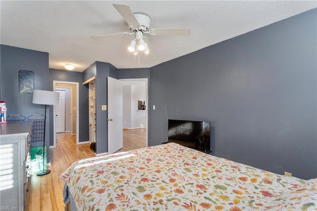 bedroom with ceiling fan, light hardwood / wood-style flooring, a closet, and a textured ceiling