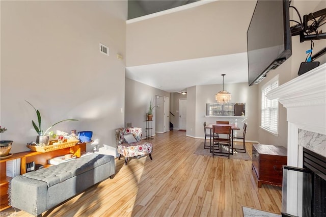 living room featuring a high end fireplace, light hardwood / wood-style floors, and a chandelier