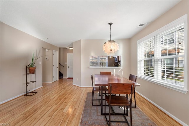 dining space featuring light wood-type flooring, a chandelier, and sink