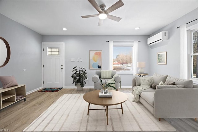 living room with ceiling fan, plenty of natural light, light hardwood / wood-style floors, and a wall unit AC