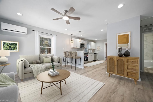 living room featuring ceiling fan, light wood-type flooring, and a wall unit AC