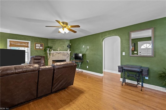 living room featuring a fireplace, ceiling fan, and light hardwood / wood-style floors