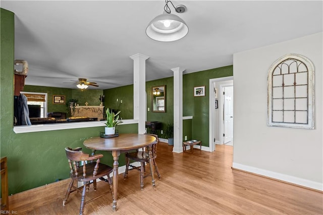 dining area with ornate columns, ceiling fan, and light hardwood / wood-style floors