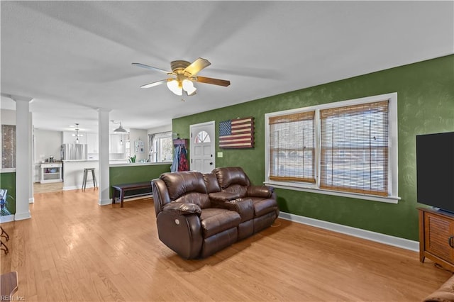 living room with ceiling fan, light hardwood / wood-style flooring, and ornate columns