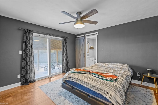 bedroom with ceiling fan, access to outside, a barn door, and wood-type flooring