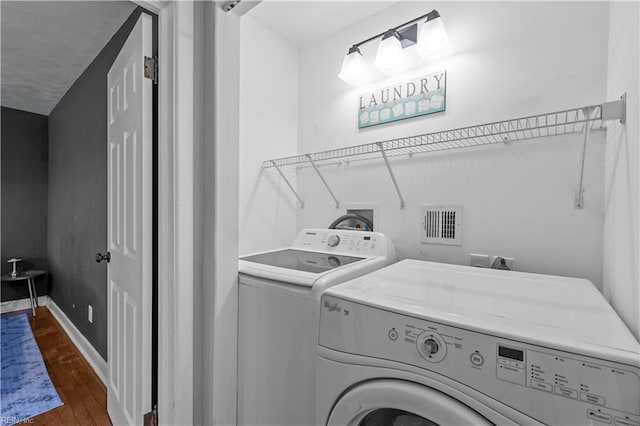 washroom with washing machine and dryer and dark hardwood / wood-style flooring