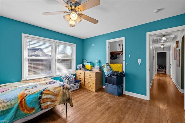 bedroom with ceiling fan, a spacious closet, a closet, and wood-type flooring