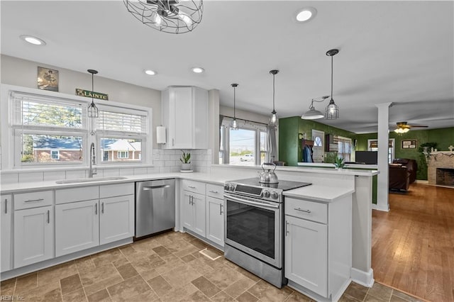 kitchen with decorative light fixtures, stainless steel appliances, white cabinets, and sink